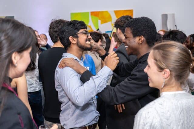 Two men greeting each other with a hug and smiling.